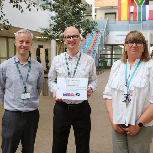 3 staff members standing with their careers mark certificate